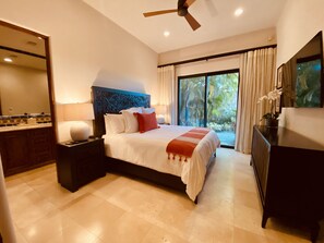 A modern hotel room with a large bed, a nightstand, a dresser, a ceiling fan, and a large window with curtains.