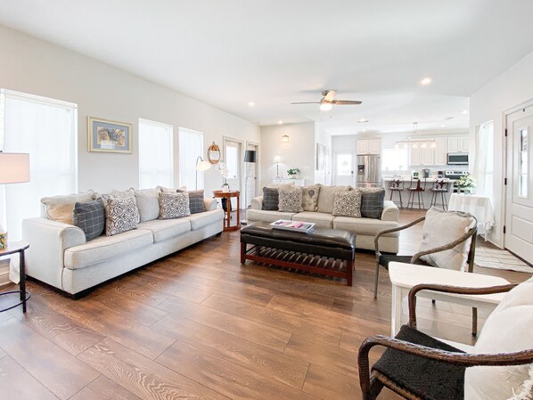 A spacious living room with a large sofa, a coffee table, and a dining area with chairs.