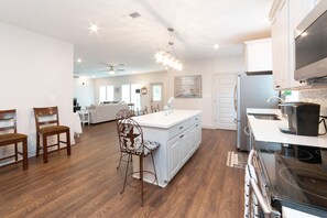 A spacious kitchen with a large island, white cabinetry, and a modern stove.