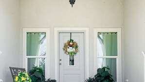 A porch with a white door, a hanging lantern, and two potted plants. - 2 mi to Old Town ★ Blocks to ⛱️ ★Spacious & Cozy (Bay Saint Louis)