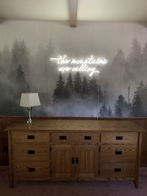 Una habitación con un armario de madera y un letrero de neón que dice 'the mountains are calling'.