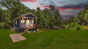 A small, single-story house with a porch and a staircase leading to a deck. - Bluebonnet Tiny Home ~ HOT TUB (Willis)