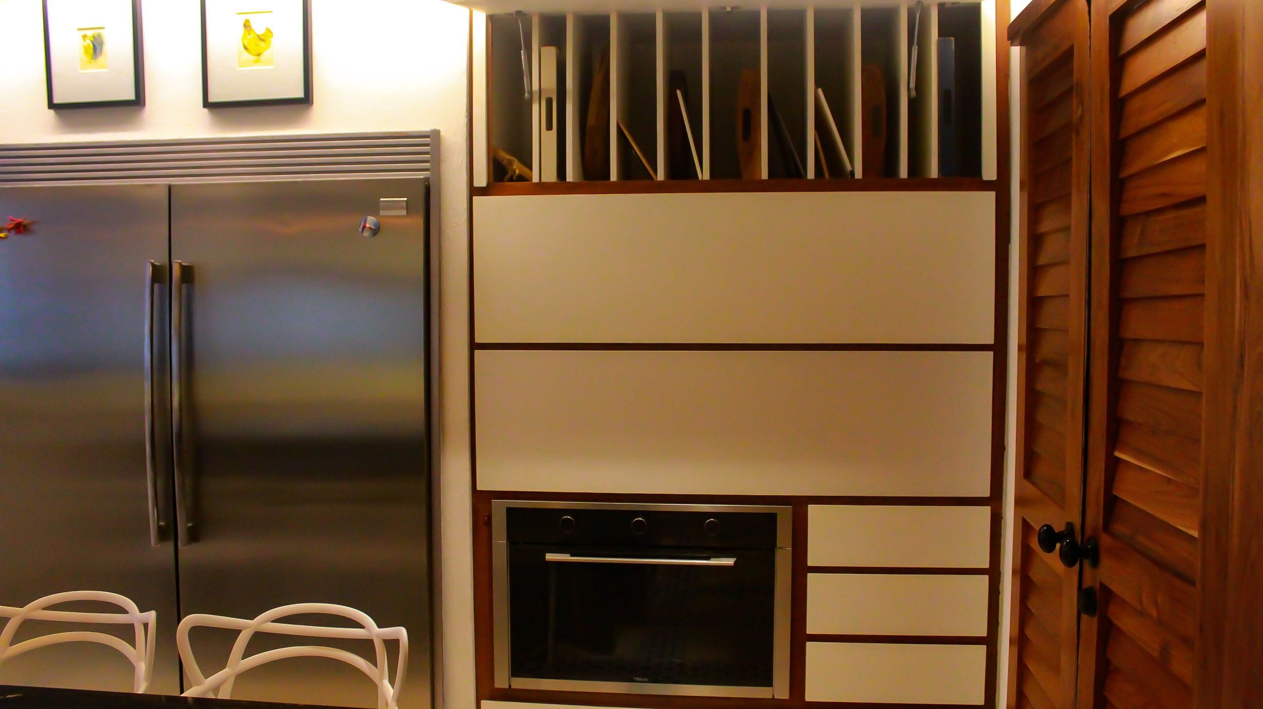 Eine kompakte Küche mit integriertem Kühlschrank, Backofen und Mikrowelle. Über dem Kühlschrank befinden sich Bilder in Rahmen.