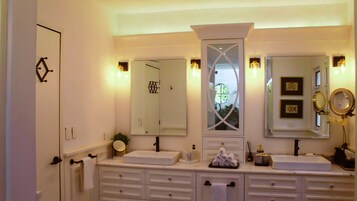 Un baño con dos lavamanos, un espejo grande y luces en la pared.
