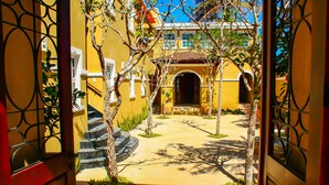 A courtyard with a yellow building, a staircase, and a gate. - Esciros Luxury Villa (Progreso)