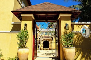 A building entrance with a tiled roof, a doorway, and potted plants. - Esciros Luxury Villa (Progreso)