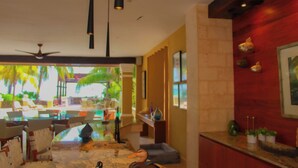 A modern hotel lobby with a glass coffee table, seating area, ceiling fan, and decorative wall elements. - Esciros Luxury Villa (Progreso)