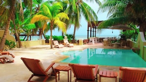 A poolside area with lounge chairs and a dining setup overlooking the ocean. - Esciros Luxury Villa (Progreso)