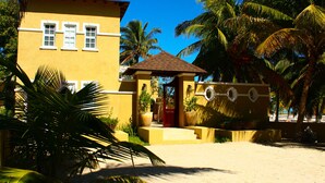 A yellow building with a red door, large windows, and a small patio area with a chair. - Esciros Luxury Villa (Progreso)