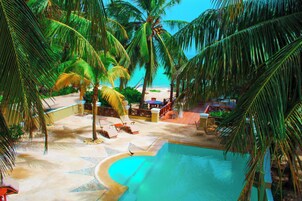 A pool area with lounge chairs and palm trees.