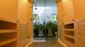 A narrow hallway with a tiled floor, two large potted plants, and a mirrored wall reflecting a circular window with green leaves. - Esciros Luxury Villa (Progreso)