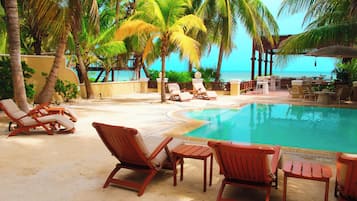 A poolside area with lounge chairs and a view of the ocean.