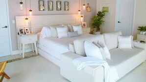 A modern bedroom with a large bed, bedside tables, a nightstand, a potted plant, and a wall-mounted light fixture. - Esciros Luxury Villa (Progreso)