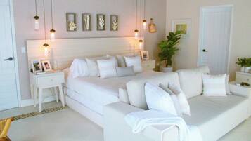 Un dormitorio moderno con una cama grande, mesitas de noche, una lámpara de pared y una planta en maceta.
