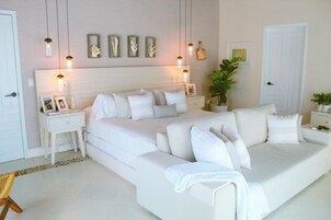 Un dormitorio moderno con una cama grande, mesitas de noche, una lámpara de pared y una planta en maceta.