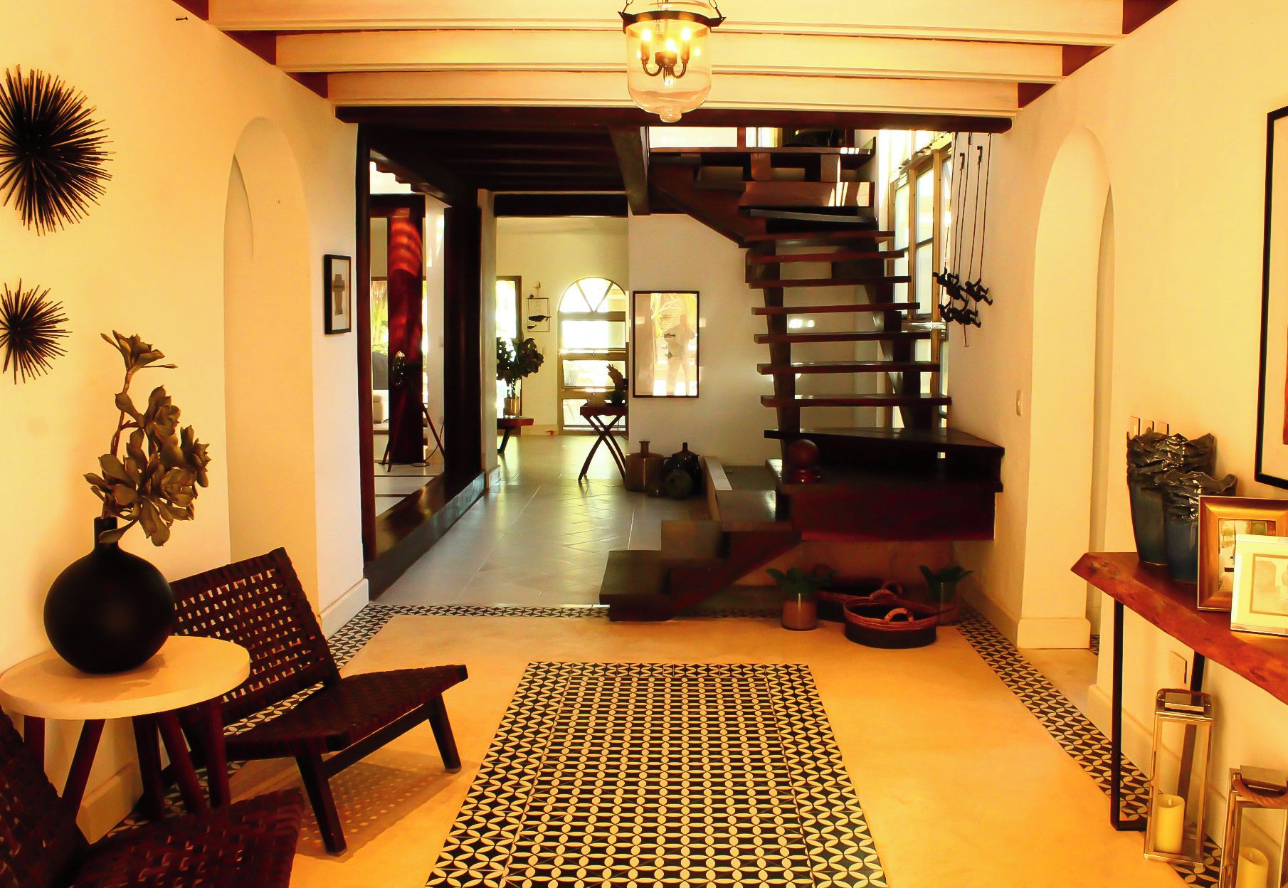 A staircase leading to an upper floor, a patterned rug, and a chair in a room with a tiled floor.