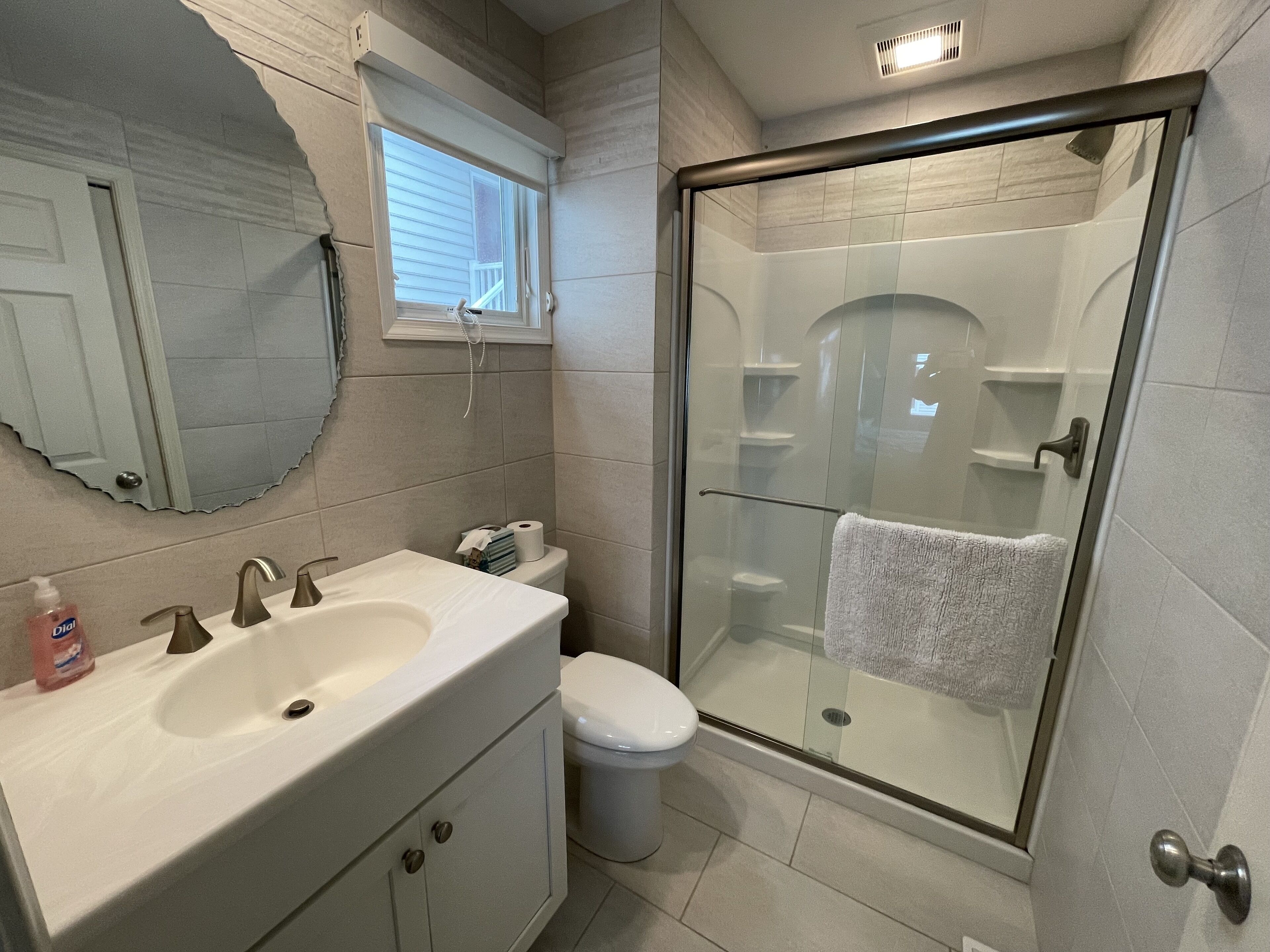 A bathroom with a sink, toilet, and glass-enclosed shower stall.