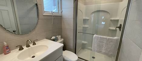 A bathroom with a sink, toilet, and glass-enclosed shower stall.