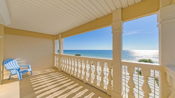 A covered balcony with a view of the ocean, a blue chair, and a patterned floor. - Sea Dreams - Amazing Beachfront 5 Bedroom Property with Gulf Front Private Pool (Panama City)