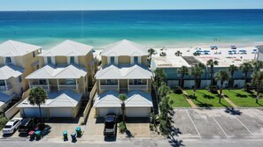 A beachfront hotel with multiple-story buildings, a parking area, and a beach with umbrellas. - Sea Dreams - Amazing Beachfront 5 Bedroom Property with Gulf Front Private Pool (Panama City)