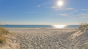 Una playa arenosa con cielo despejado y sol radiante.