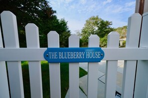 Una cerca blanca de piquetes con un cartel que dice "The Blueberry House".
