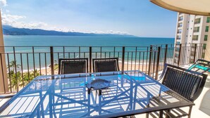 A balcony with a table and chairs overlooking a beach and ocean. - Stunning views over the bay from Grand Venetian  (Puerto Vallarta)