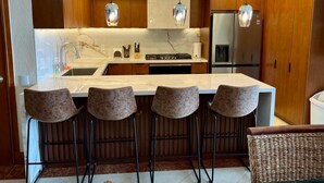 A modern kitchen with a marble countertop, stainless steel appliances, and wooden cabinets. - Stunning views over the bay from Grand Venetian  (Puerto Vallarta)