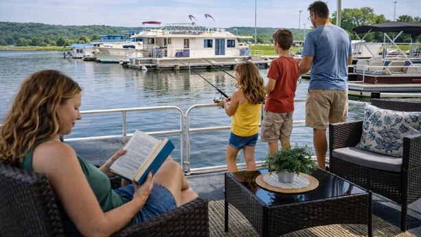 Un espace extérieur aménagé avec des meubles en osier, une table agrémentée d’une plante et offrant une vue sur les bateaux qui naviguent.