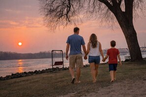 A family walking along a lakeside path during sunset.
