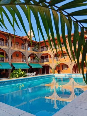 Un edificio de varios pisos con una piscina al frente.