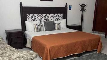 Une chambre à coucher avec un lit, une table de chevet, une chaise, un tapis et un tableau accroché au mur.