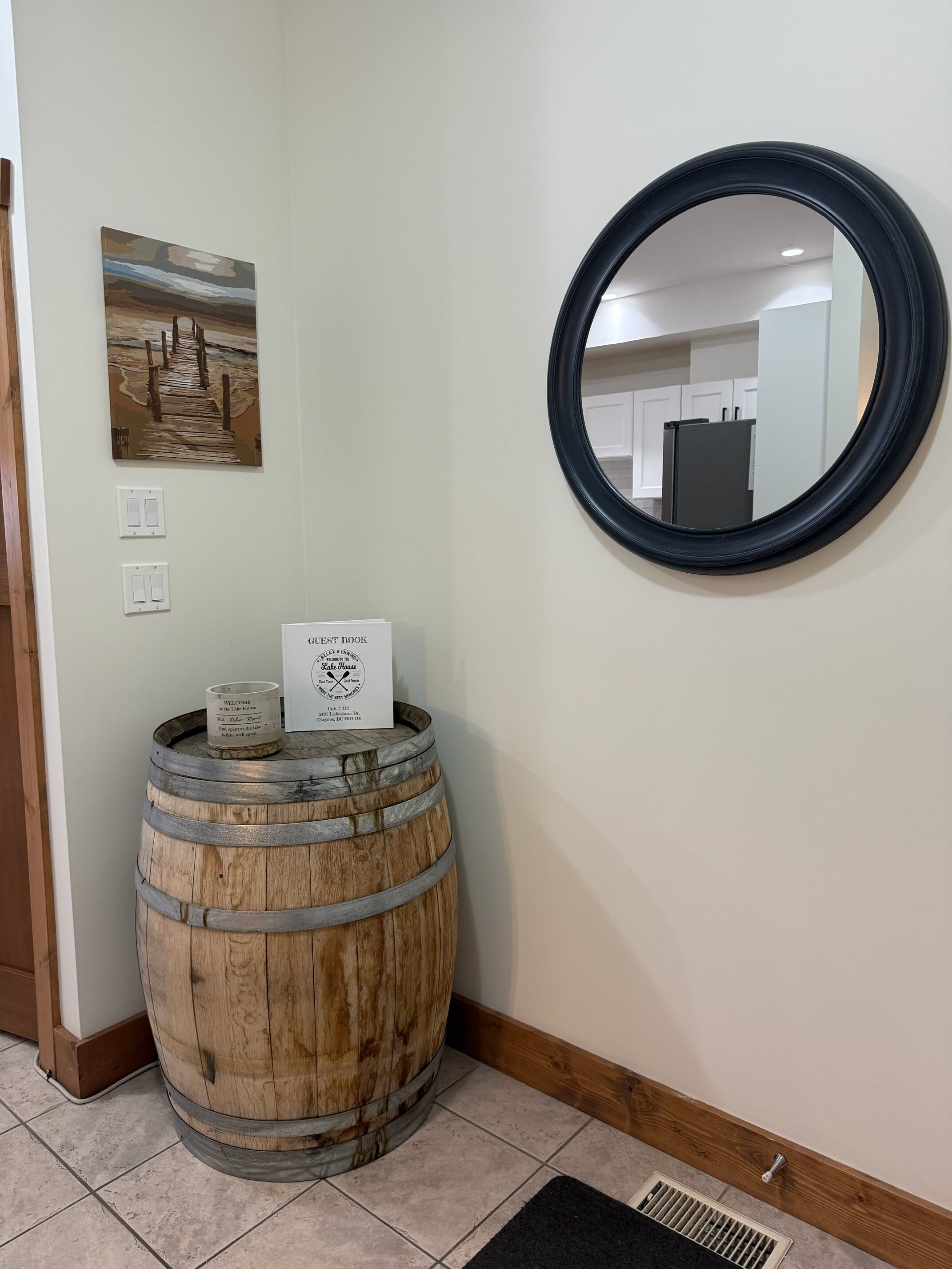 Un tonneau en bois, une pancarte de bienvenue et un miroir rond accroché au mur.
