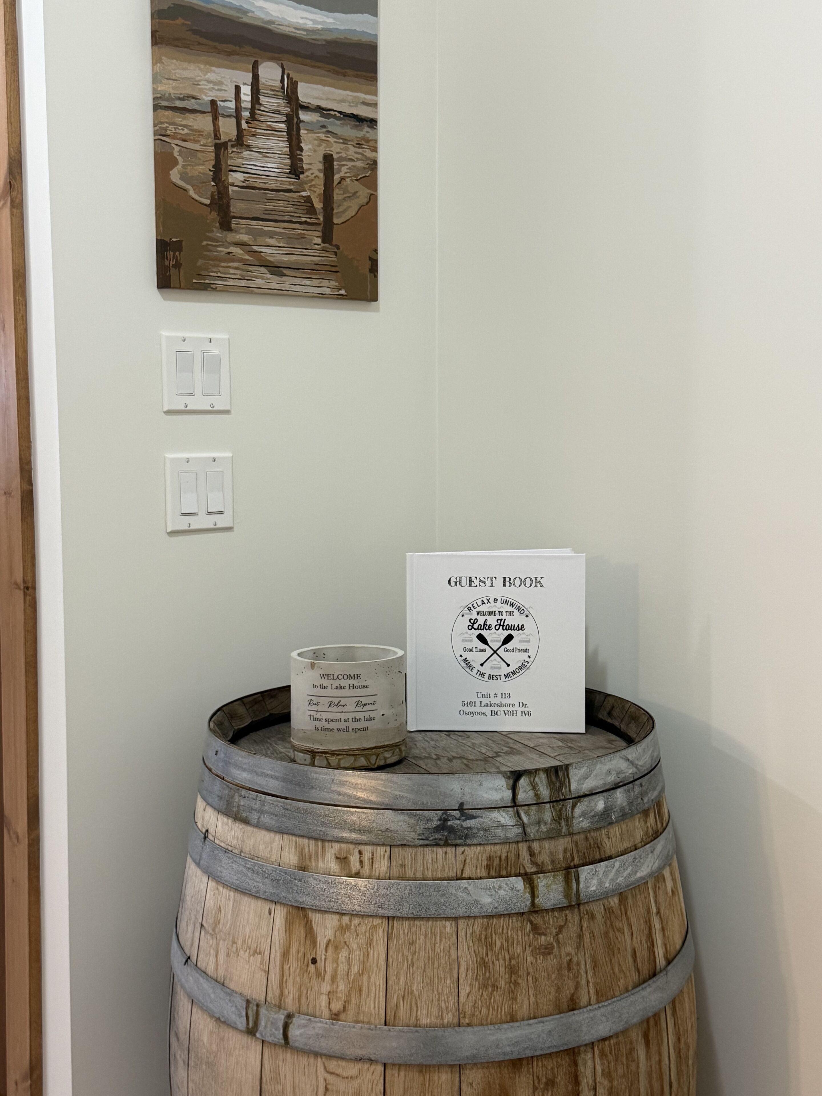 A guest book, a painting, and a wooden barrel on a wall.