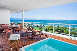A balcony with a pool, chairs, and a table.