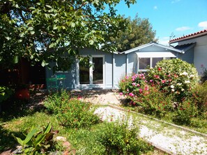 A house with a front door, a small porch, and a garden with various plants and flowers.