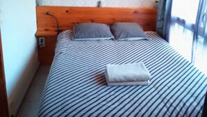 Un dormitorio con cabecera de madera, colcha estampada y una sola almohada.