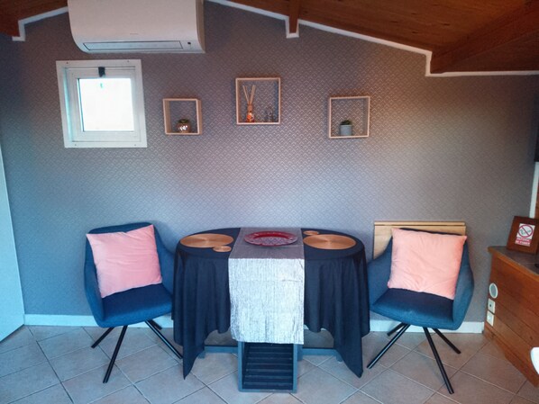 A dining area with a table, chairs, and a wall-mounted air conditioning unit.