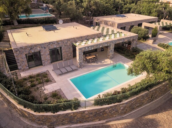 A modern building with a pool, stone facade, and outdoor seating area. - Ouzo Stone House 2, with private pool (Lesvos)