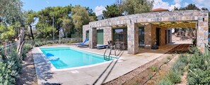 A pool area with a stone building, outdoor seating, and a pergola. - Ouzo Stone House 2, with private pool (Lesvos)