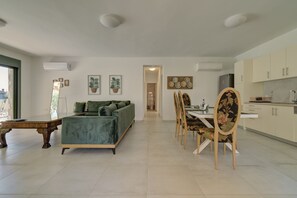 A modern living room with a green sofa, dining table with chairs, and a kitchen area. - Ouzo Stone House 2, with private pool (Lesvos)
