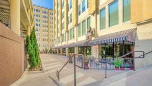 A building with a covered outdoor seating area, a staircase, and a row of windows. - Rustic Realm/2BR2Bath/KayBaileyCenter/Pool/GYM (Dallas)
