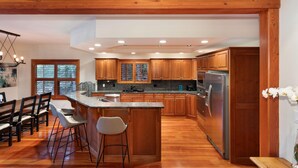 A modern kitchen with wooden cabinets, a granite countertop, and stainless steel appliances. - Luxury 5 Bedroom Blueberry Chalet (Whistler)