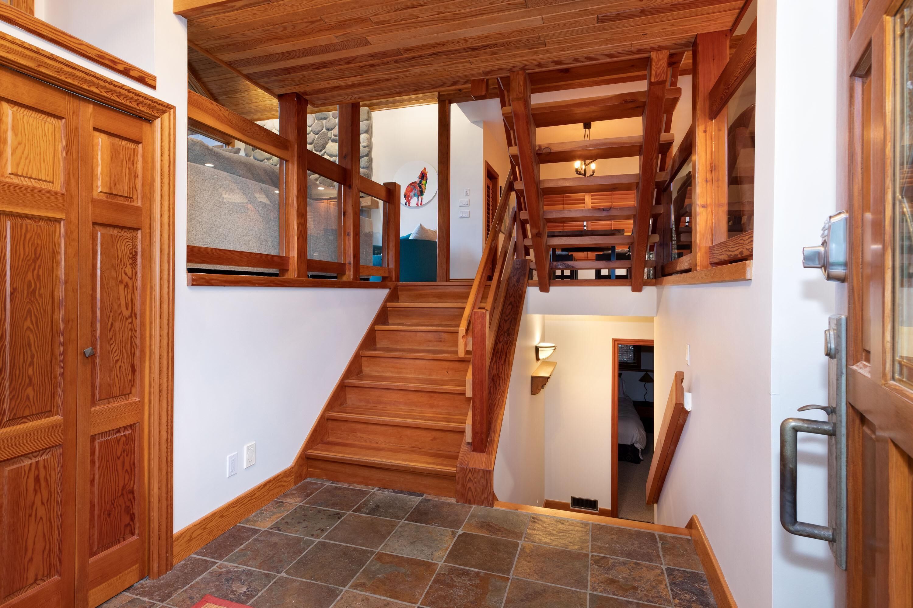 Una escalera de madera con piso de losas de piedra que conduce a un rellano en el segundo piso.