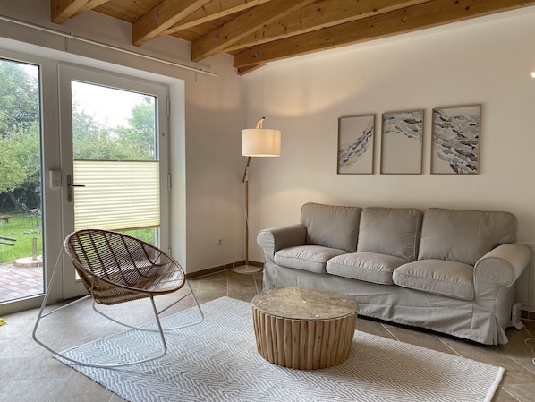 A living room with a sofa, a chair, a lamp, and artwork on the wall.