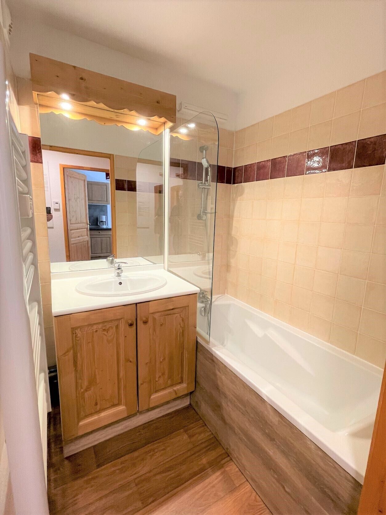 A bathroom with a wooden vanity, two sinks, a glass-enclosed shower, and a bathtub.
