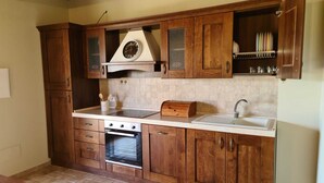 A kitchen with wooden cabinets, a built-in oven, a sink, and a clock on the wall.