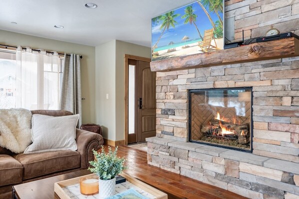 A living room with a stone fireplace, a sofa, and a coffee table.