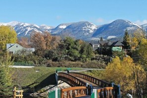 Un barrio residencial con casas, un puente y montañas nevadas al fondo.