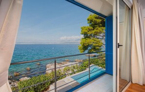 Ein Balkon mit freiem Blick auf das Meer, ein Schwimmbad und ein Baum.